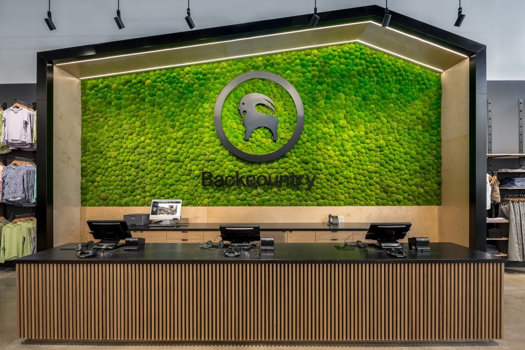Custom moss wall with metal Backcountry logo at checkout counter.