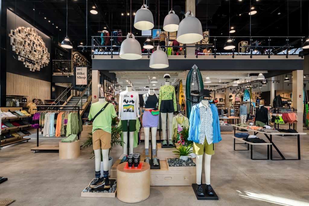 Interior of Backcountry retail space. Main entrance featuring full sales floor and custom branded featuures with hiking clothing display.