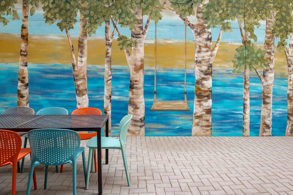 Exterior image of common courtyard featuring custom mural and outdoor seating