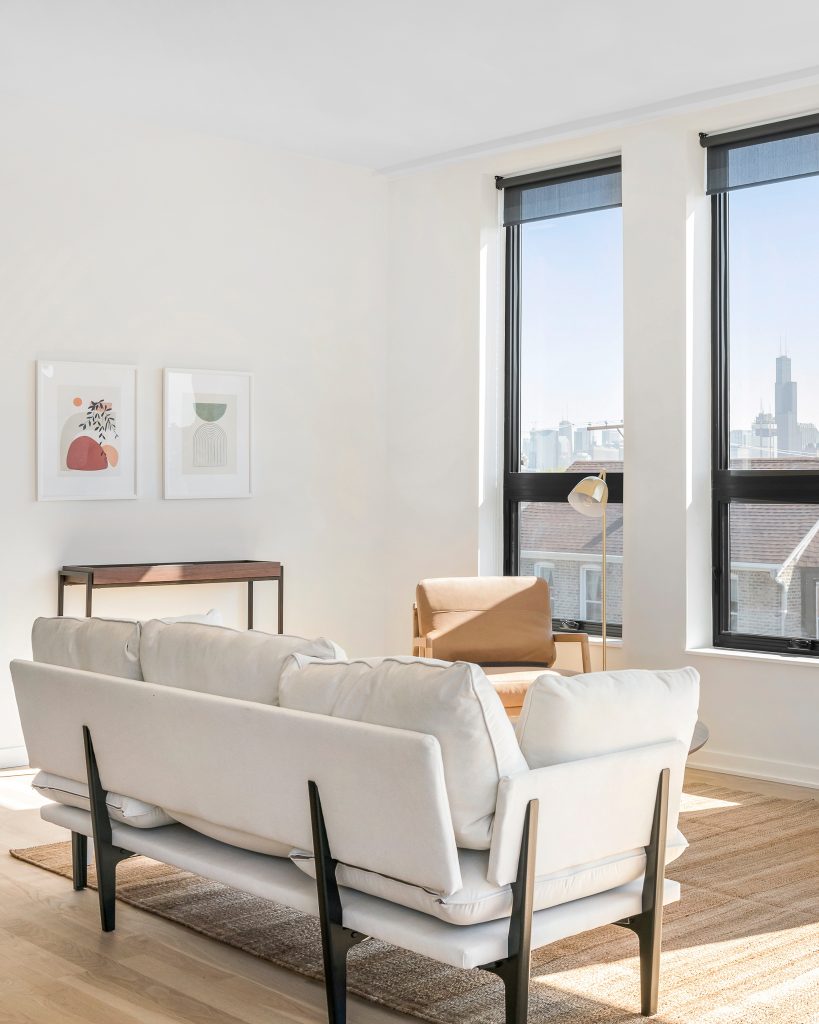 Light and bright minimal living room with mid century modern furniture and a view of the Willis Tower in the window
