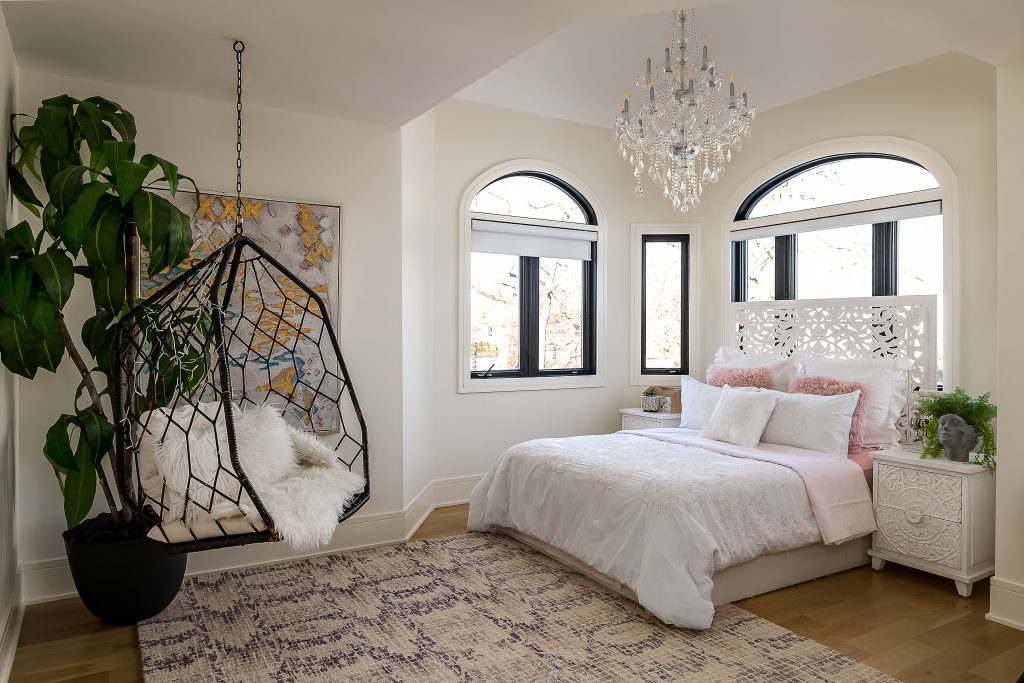 Soft and feminine bedroom with crystal chandelier and hanging egg chair.