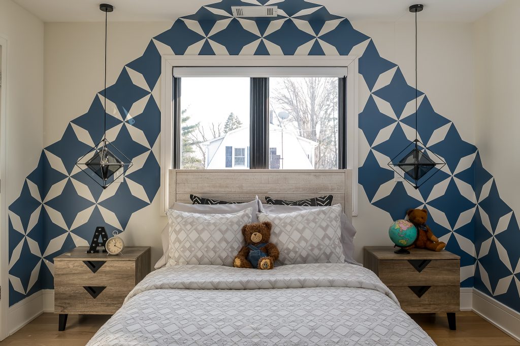 Child's bedroom with bold graphic wallpaper and teddy bear on bed.