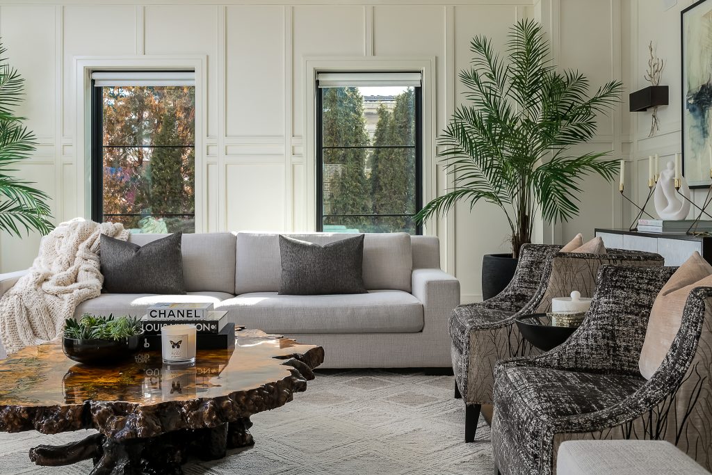 Modern living room with neutral furniture, large plants, and styled live edge wood coffee table.