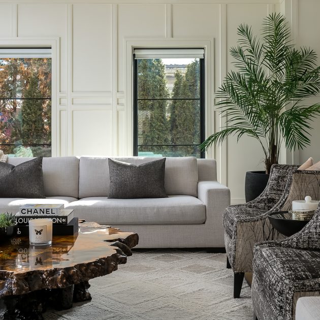 Modern living room with neutral furniture, large plants, and styled live edge wood coffee table.