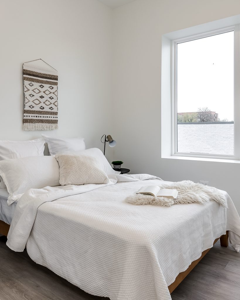 White minimalist bedroom with cozy bedding and open book