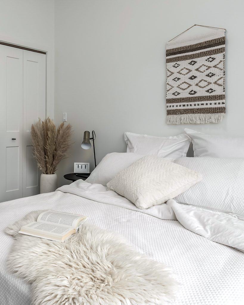 White minimalist bedroom with cozy bedding and an open book