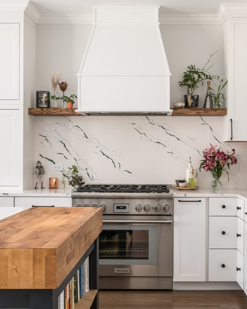 Modern white kitchen with butcher block counter and luxury brand appliances.