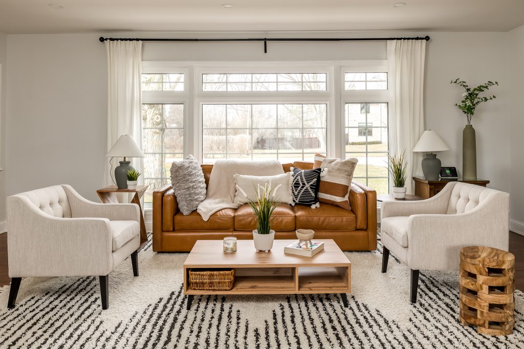 Boho minimalist living room with leather couch and neutral side chairs