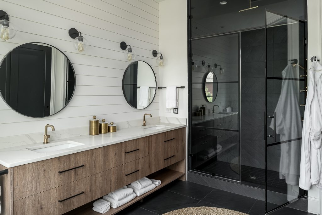 Organic Modern Primary Bathroom with walnut double vanity and black tiled walk in shower