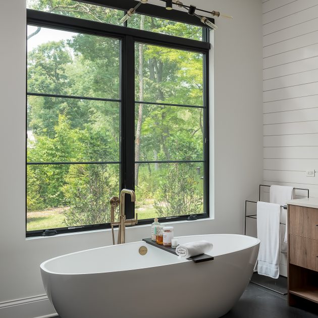 Free standing tub next to large picture window