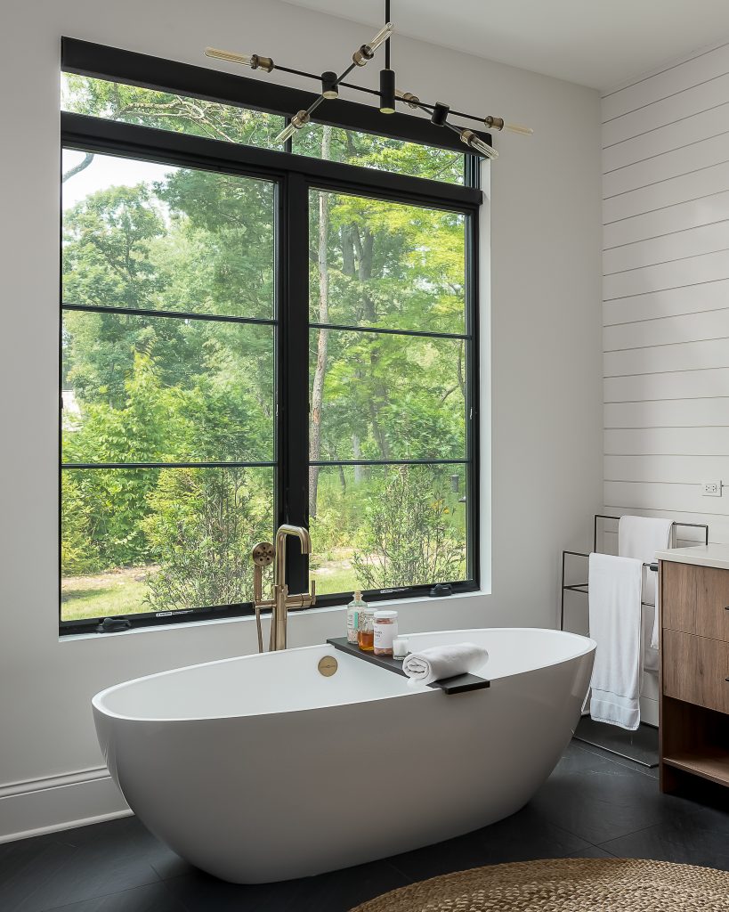 Free standing tub next to large picture window
