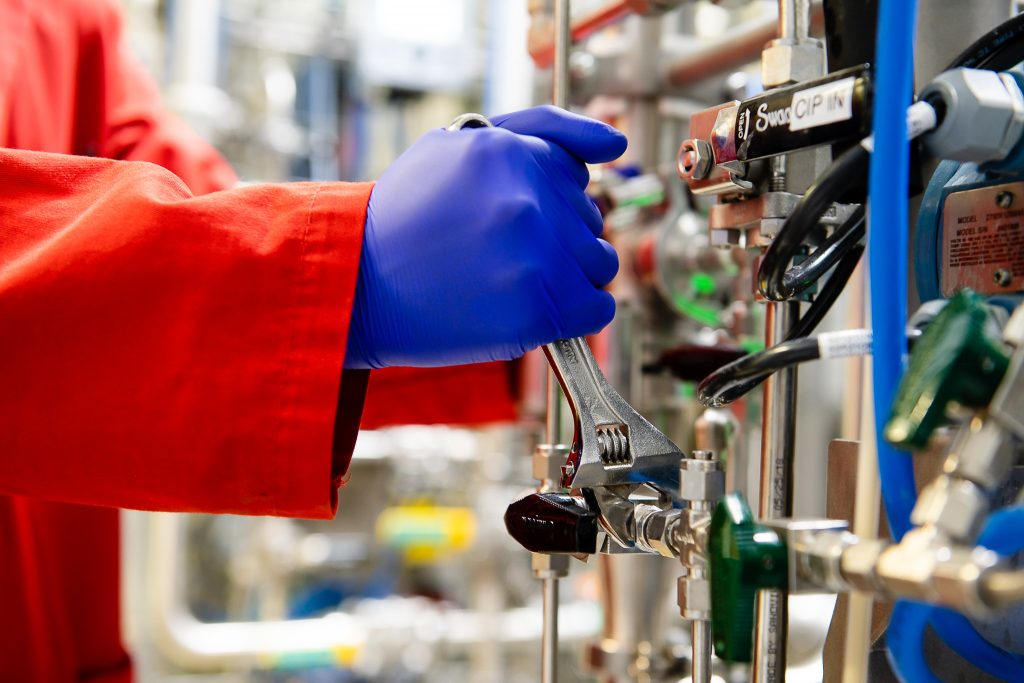 Close up of hand with glove using a wrench to adjust laboratory machinery