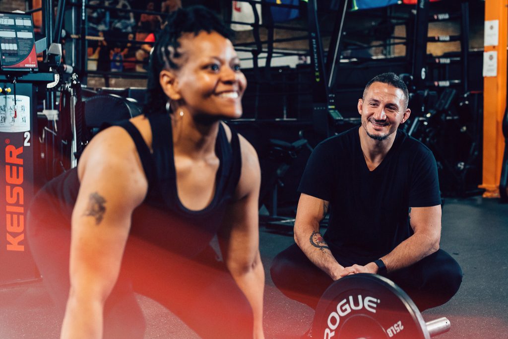 Trainer observes client in deadlift