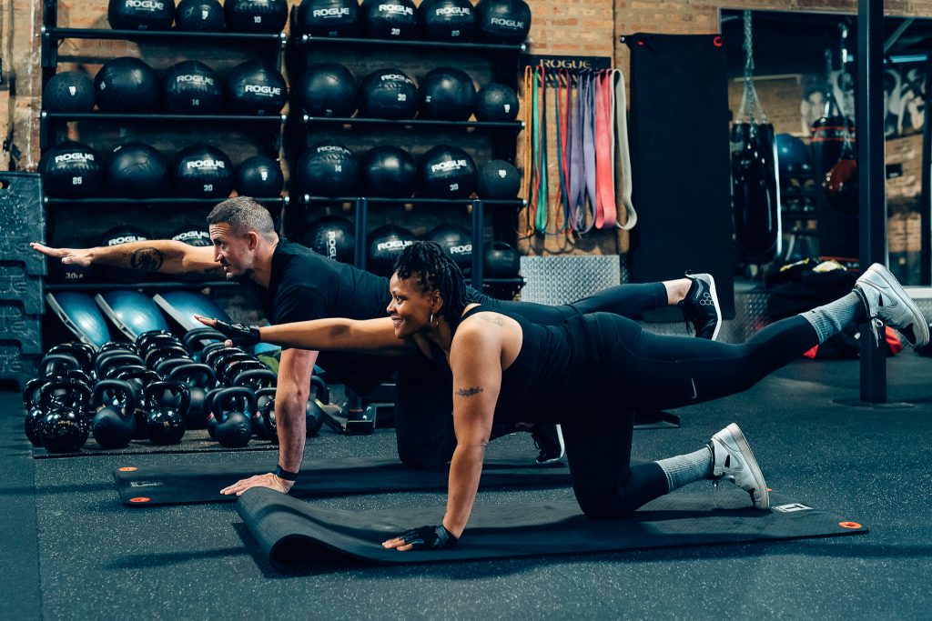 Trainer and client stretching together