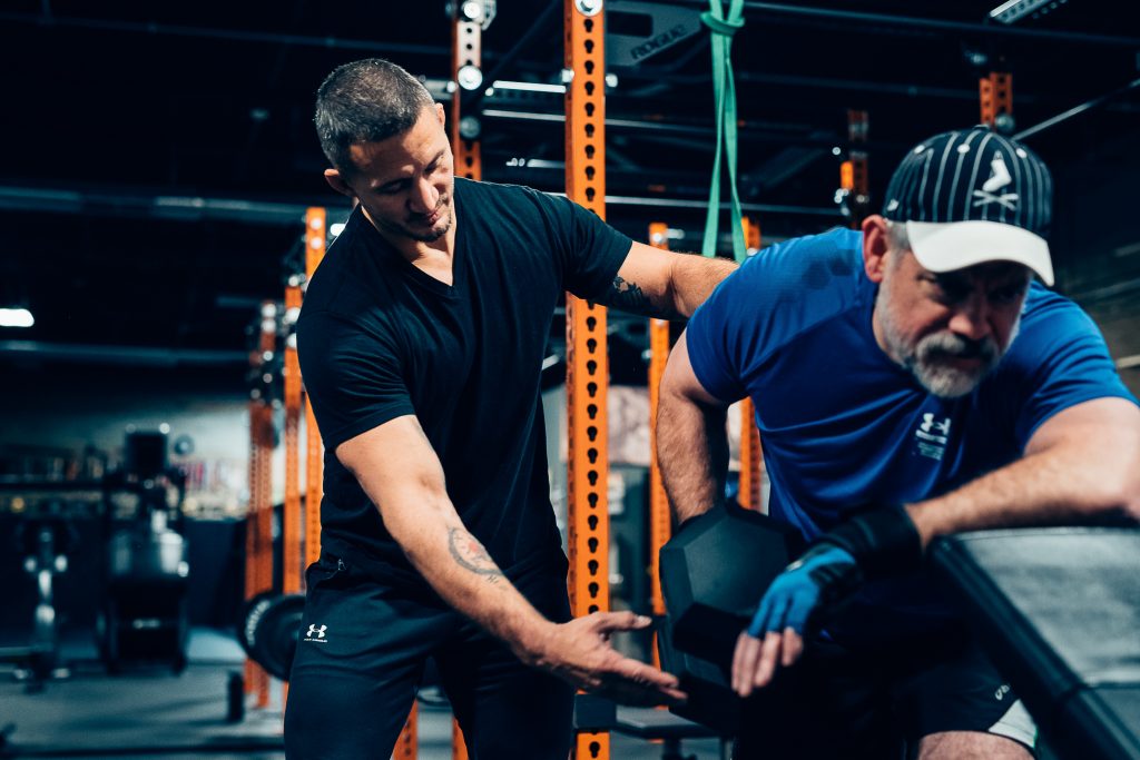 Trainer demonstrating proper weightlifting form to client.