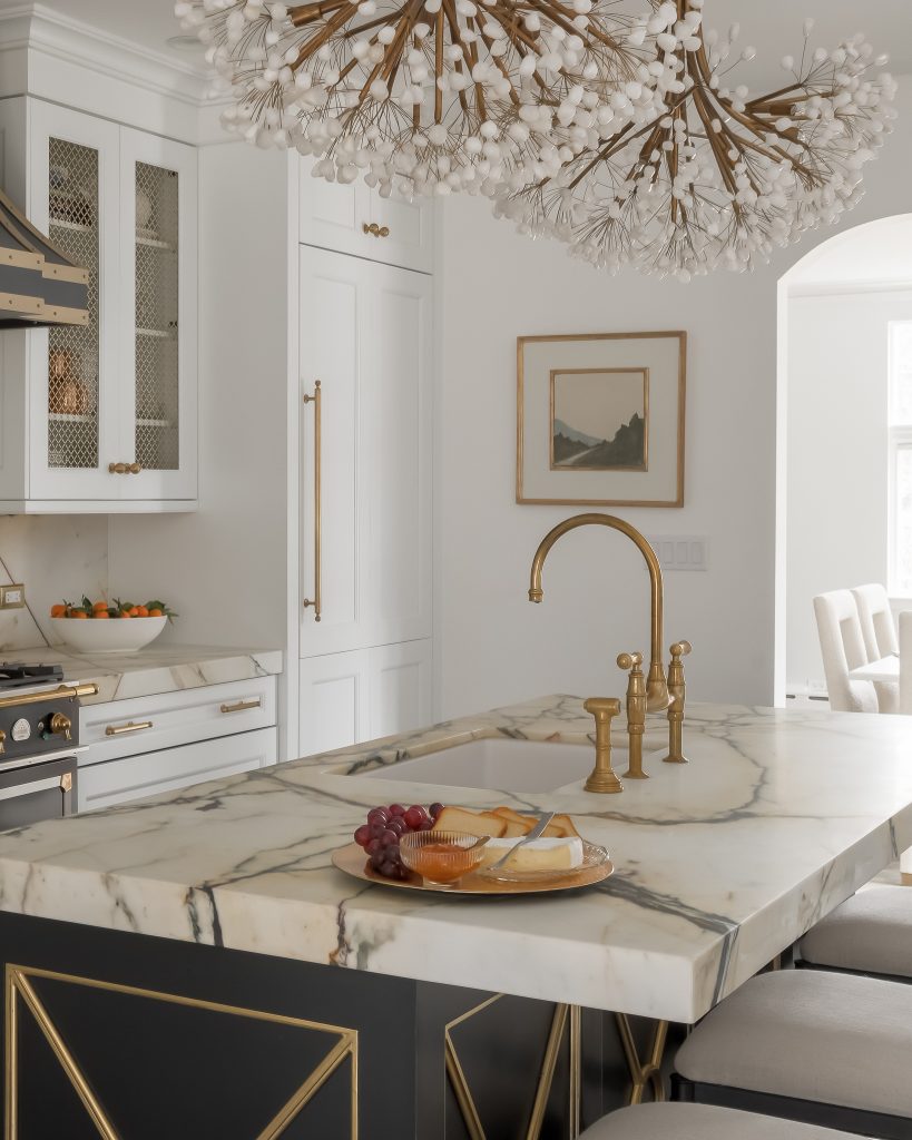 Modern glam kitchen design with black and white cabinets with gold trim and custom chandeliers