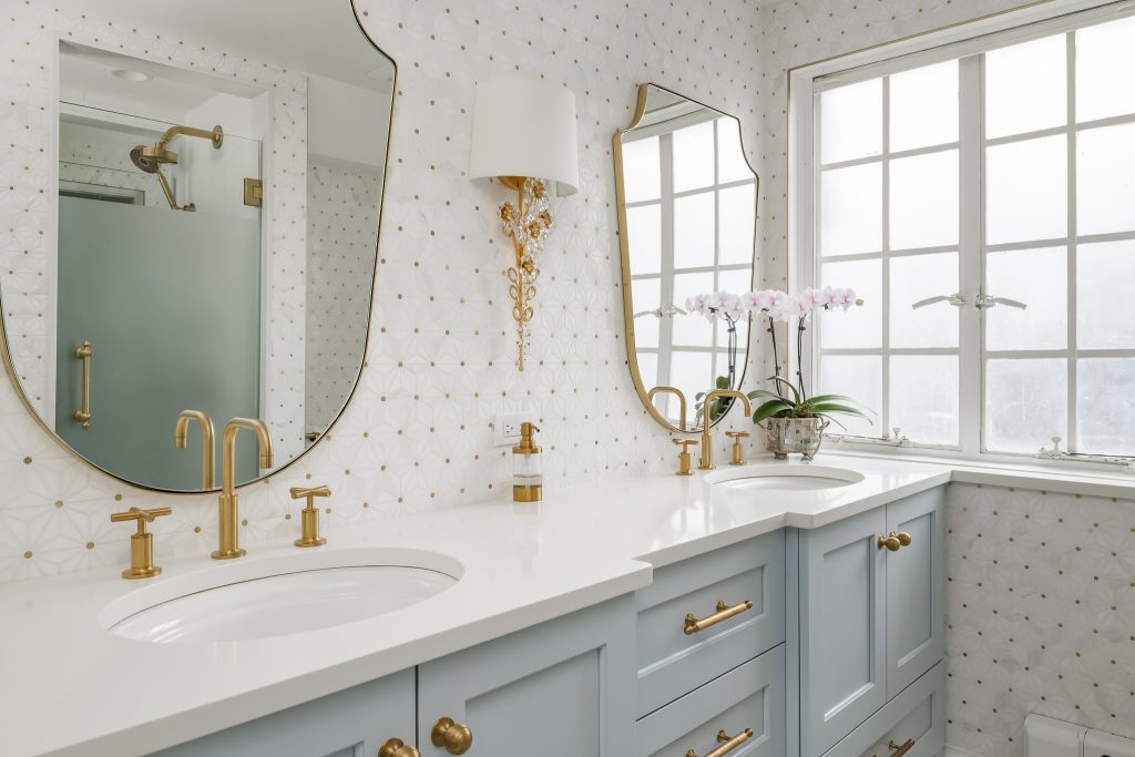 Modern glam bathroom with powder blue cabinets and gold hardware