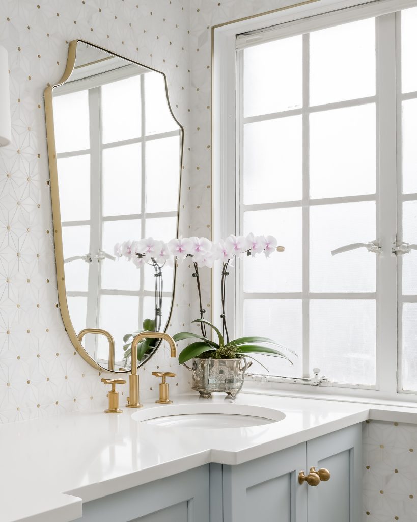 Modern glam bathroom with powder blue cabinets and gold hardware